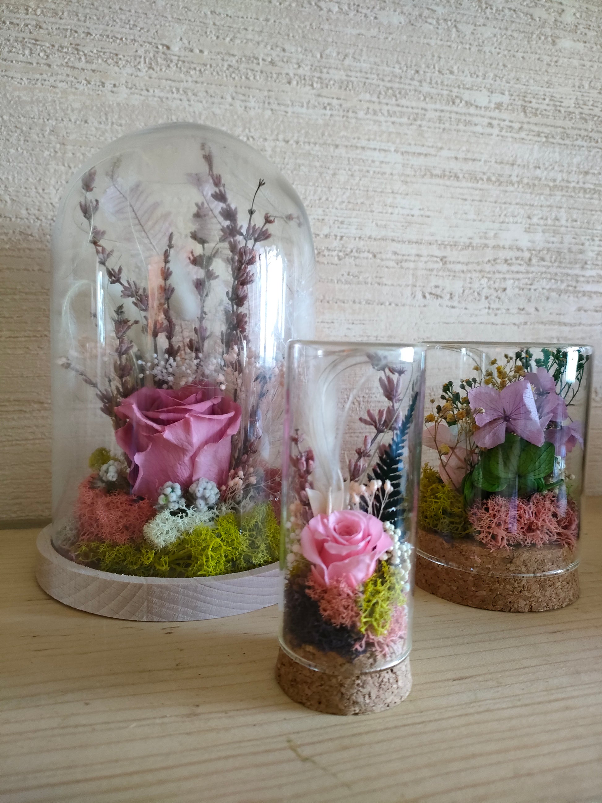 Campana in vetro con rosa stabilizzata al centro, composizione floreale botanica elegante.
